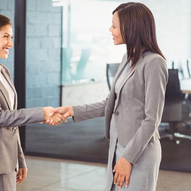 Two young women executives shaking hands